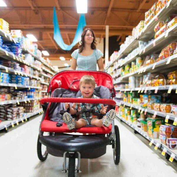 A woman shops in a grocery store while pushing a stroller with a child